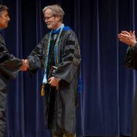 Robert Smart and faculty member shaking hands, Provost applauding